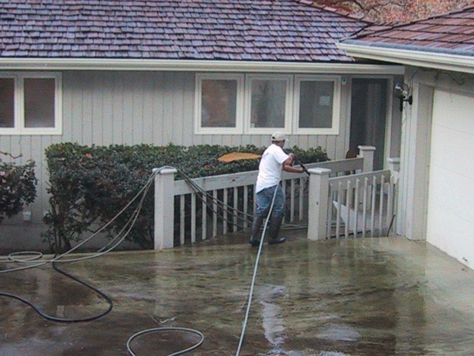 Pressure washing the exterior of a residential house to remove dirt and stains.