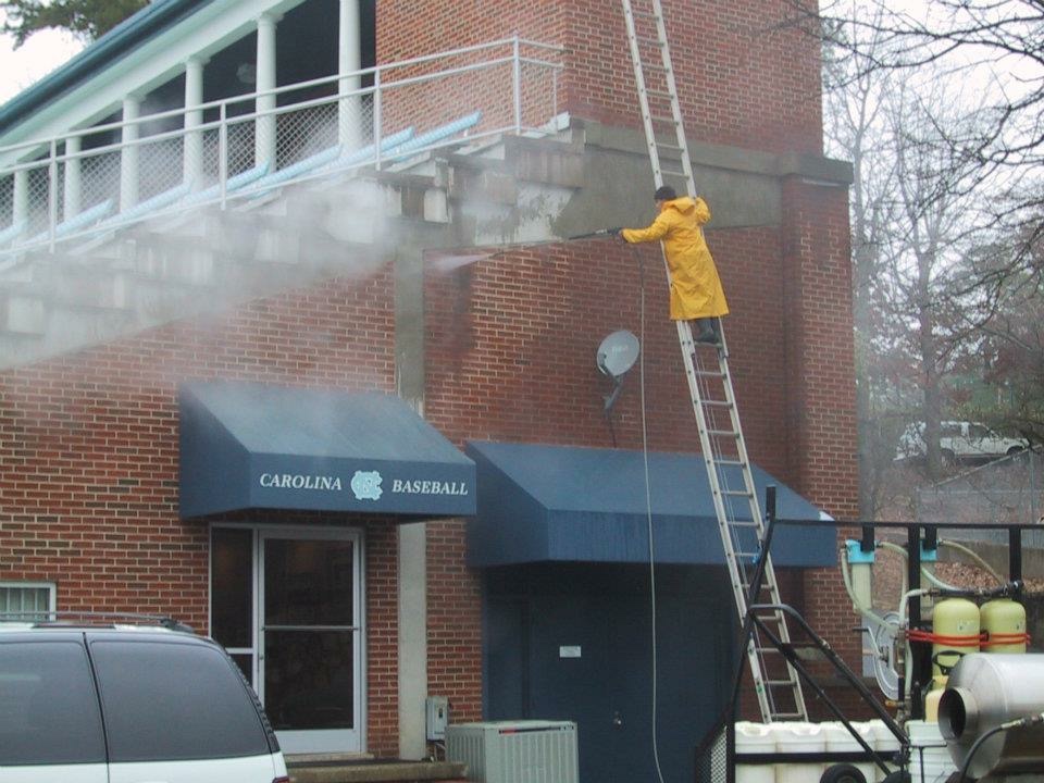 Pressure washing the exterior of UNC Baseball Stadium to remove dirt and stains.