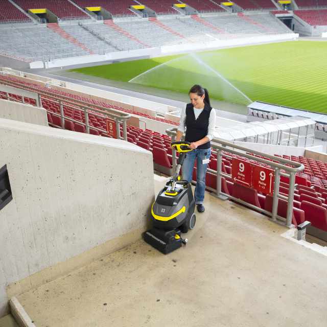 Power washing a stadium interior, removing dirt and stains.