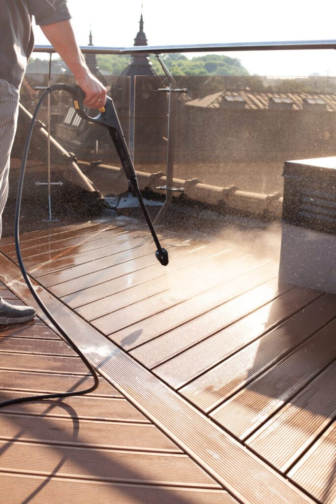 Pressure washing a wooden deck to remove dirt and grime, restoring its natural look.